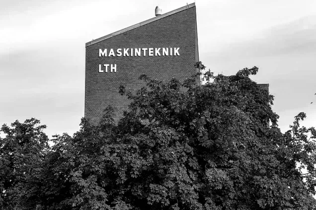 M-huset i svartvitt med buskage i förgrunden. Foto.